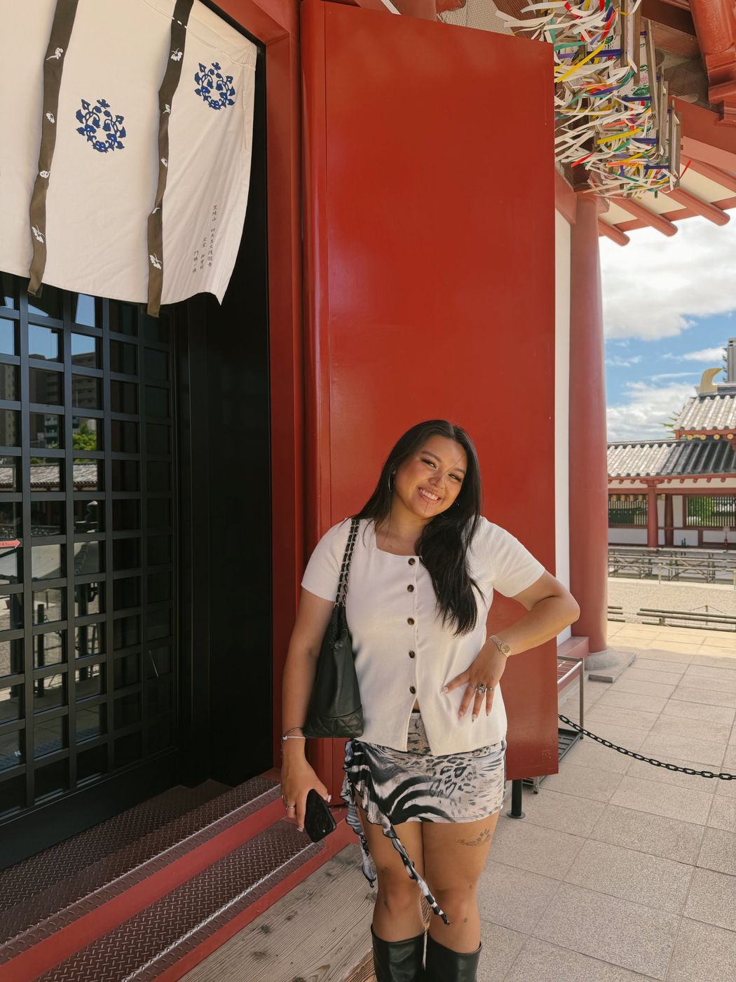 Carla smiling in front of a red temple wall in Japan
